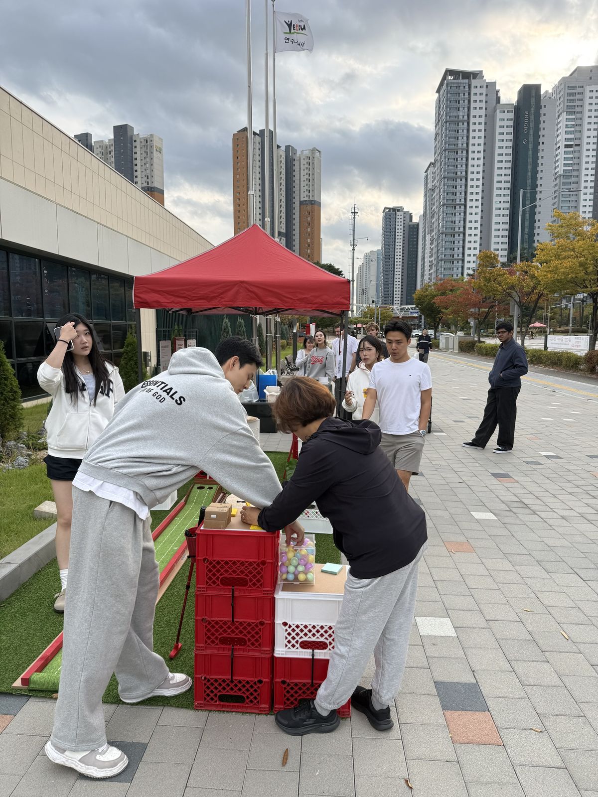 People at the wish station choosing a capsule from the clear box on the crate table.